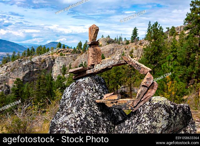 Medium shot of unusual inukshuk stone figure stands balanced on rock. Structure made with rocks, Okanagan Valley, British Columbia, Canada