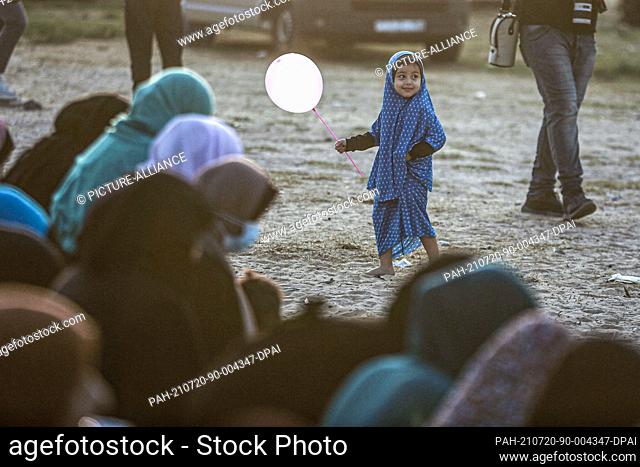 20 July 2021, Palestinian Territories, Gaza City: A Palestinian girl plays with a balloon during Eid al-Adha morning prayer at Al-Saraya Square