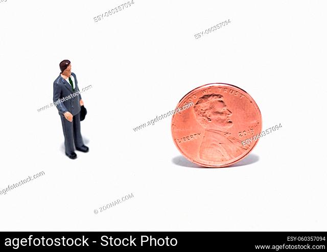 Small plastic people looking at a penny
