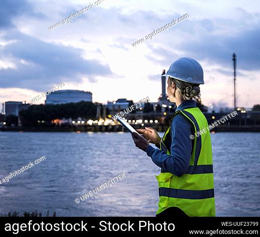 Hembra madura celebración profesional tableta digital mientras está de pie junto al río