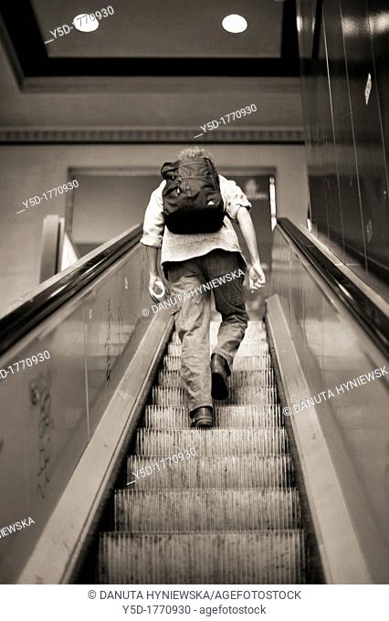 traveller climbing up an escalator, a man with backpack, Cornavin - main railway station in Geneva, Switzerland