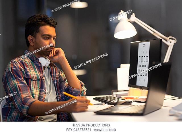 creative man with laptop working at night office