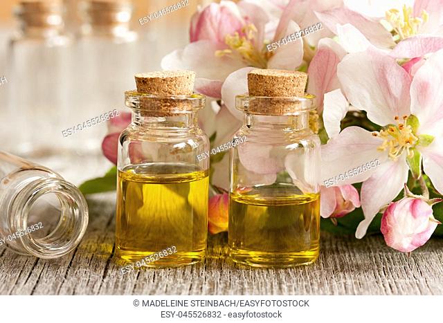 Two bottles of essential oil with apple blossoms in the background