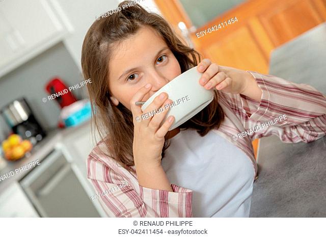 morning, a teenage girl is drinking coffee in a bowl