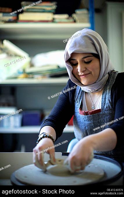 Young Muslim woman in hijab at pottery wheel