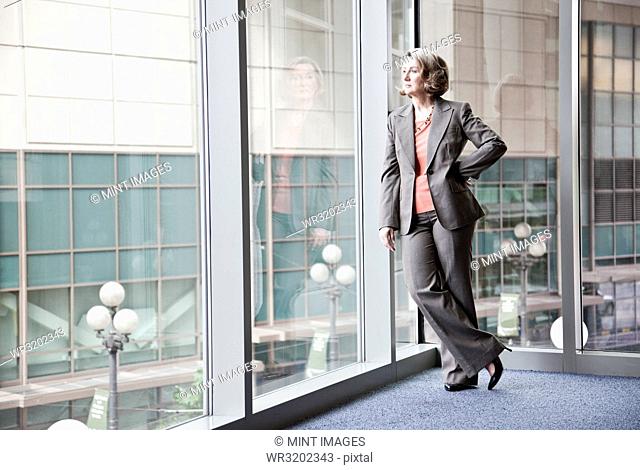 A Caucasian businesswoman standing next to a large window in a convention centre lobby