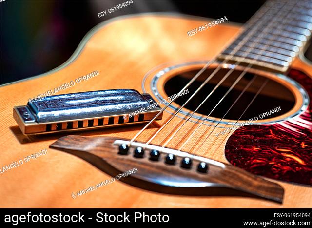 Acoustic guitar with country blues harmonica ready on stage