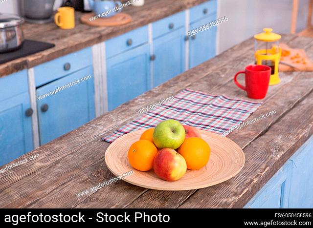 View on the wooden table at kitchen with fruit and teaspot on it. Picture of cuisine with table on front view