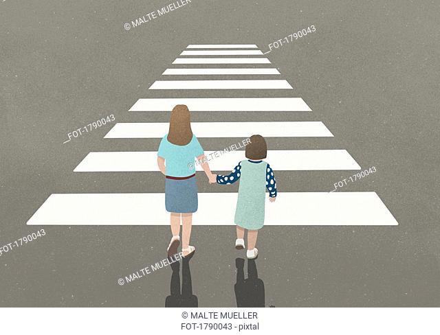 Woman and girl holding hands whilst walking through zebra crossing