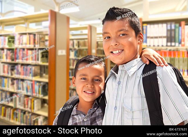 Happy young hispanic student brothers in library