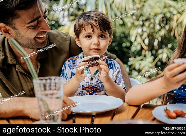Innocent boy with cupcake by smiling father on party