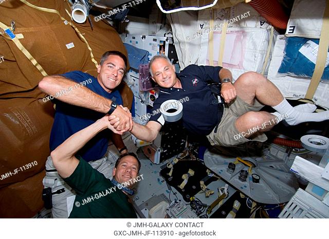 Astronauts Christopher Cassidy (left), Dave Wolf (right)and Tom Marshburn (bottom), all STS-127 mission specialists, share a moment shaking hands with one...