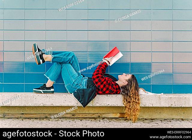 Teenage girl reading book outdoors