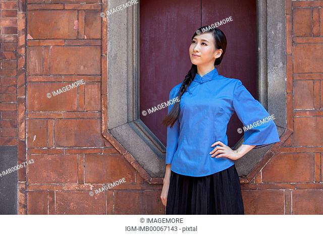 Young woman with cheongsam standing and looking away