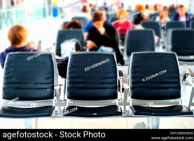 Airport lounge empty chairs. Blurred people waiting for departure