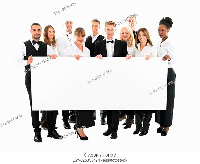 Portrait of confident restaurant staff holding blank billboard against white background