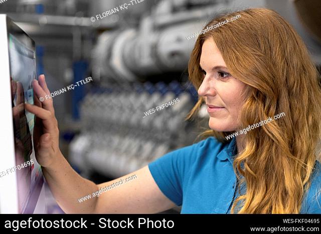 Blond IT technician using touch screen device in factory
