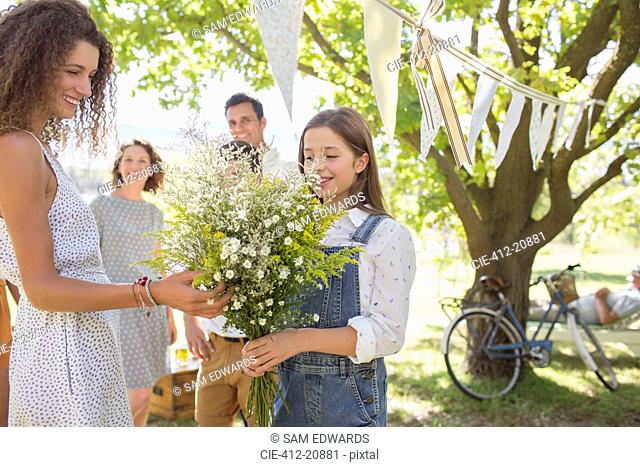 Woman admiring flowers held by young girl