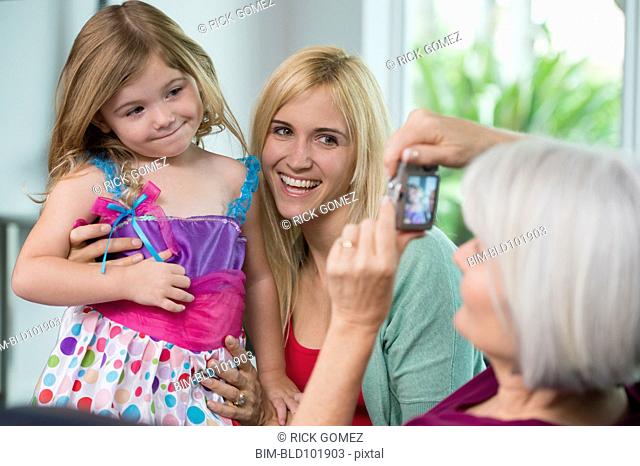 Smiling Caucasian grandmother, mother and daughter taking pictures