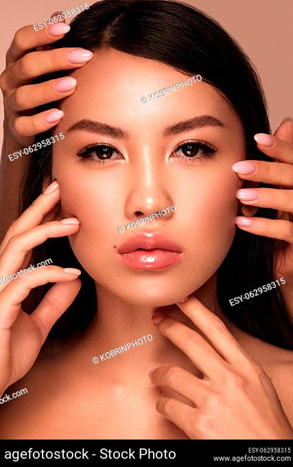 Beautiful delicate woman of oriental type with nude makeup and perfect skin. Beauty face. Spa salon