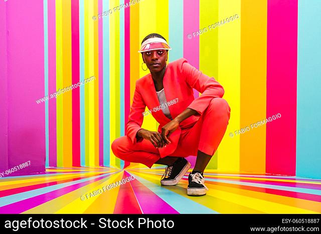 Beautiful african american young woman dancer having fun inside a rainbow box room - Cool and stylish afro adult woman portrait on multicolored background