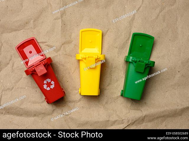 three multi-colored plastic containers on a brown paper background, concept of correct sorting of garbage for further recycling