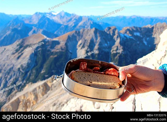 Hike to the Pleisenspitze (2569m), woman's hand holds a lunch box with bread and sausage, mountain tour, mountain hiking, outdoor