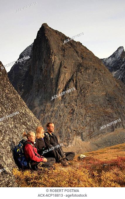 Hikers taking a break on rock while climbing in Tombstone Territorial Park, Yukon, Canada