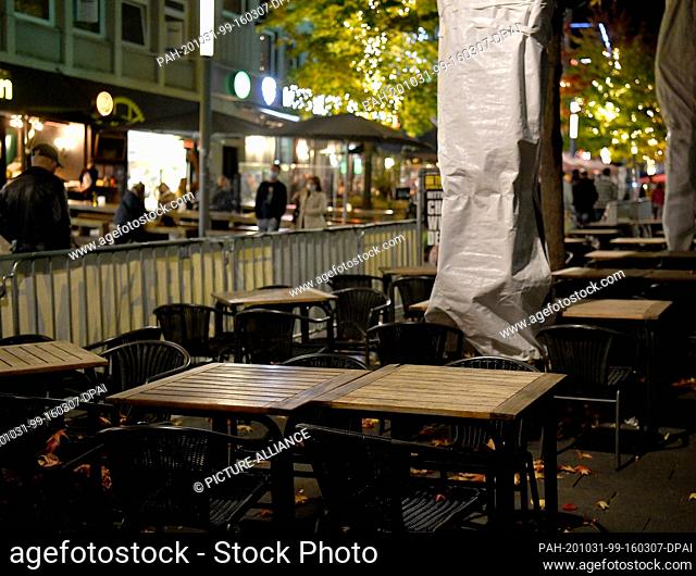 31 October 2020, North Rhine-Westphalia, Bochum: Chairs and tables are located in the Bermuda3eck nightlife area outside an already closed restaurant