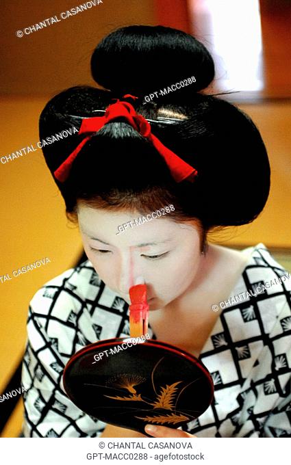 A MAIKO APPRENTICE GEISHA WITH HER TRADITIONAL MAKEUP DORAN. APPLICATION WITH A BAMBOO BRUSH BURASHI OF A PINK MAKE-UP TO MODEL THE FEATURES