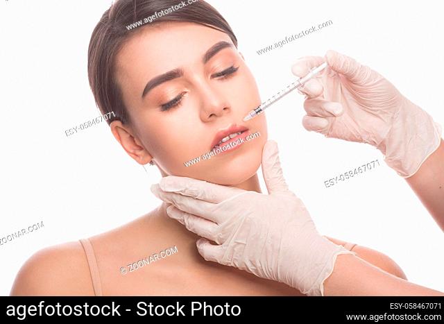 Closeup of beautiful woman getting injections in her lips. Full lips. Beautiful face and syringe. Plastic surgery and cosmetic injection concepts