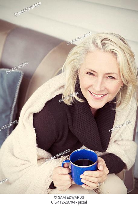 Portrait smiling senior woman wearing shawl drinking coffee on patio