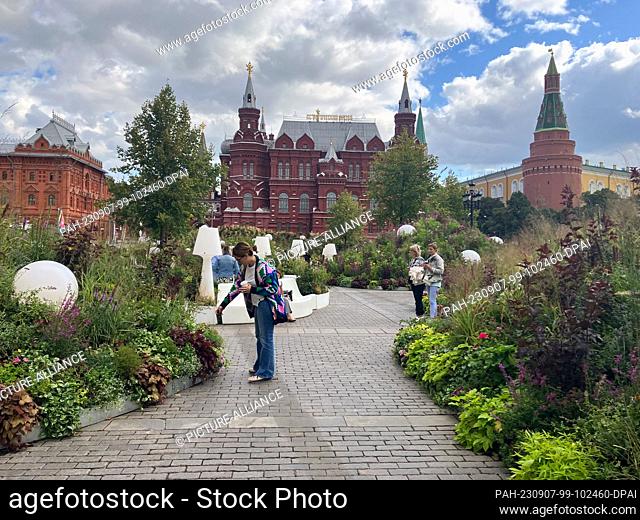 PRODUCTION - 06 September 2023, Russia, Moskau: People walk between flowerbeds not far from Red Square in Moscow. In the midst of war