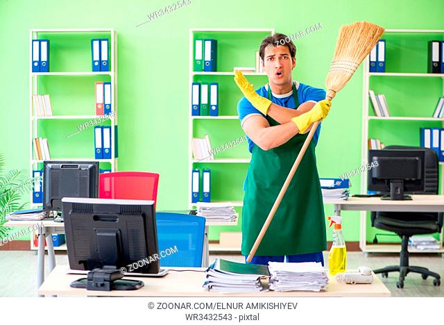 Young male handsome professional cleaner cleaning floor with broom