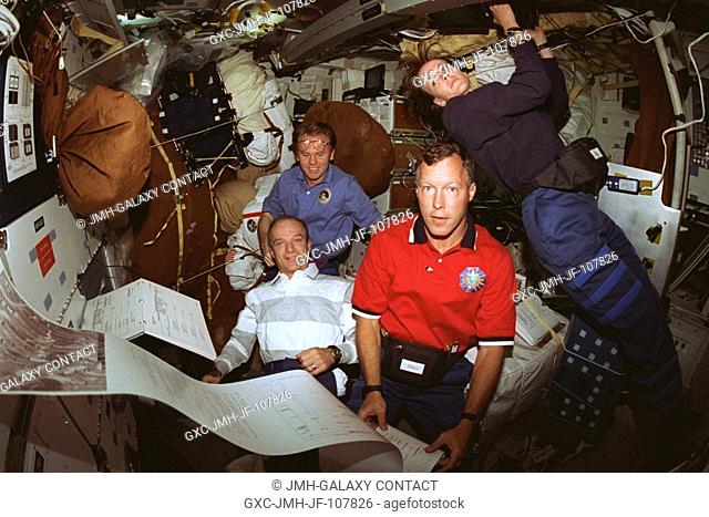 Four of the seven STS-91 crew members check the morning mail on the mid deck of the Earth-orbiting Space Shuttle Discovery toward the end of the scheduled...