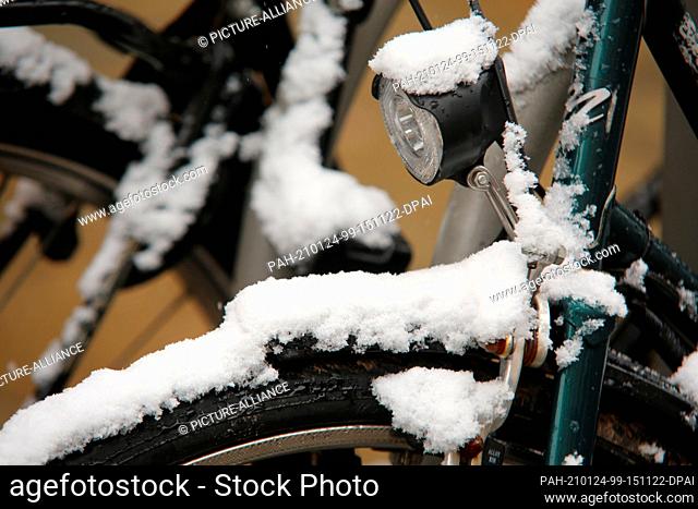 24 January 2021, Saxony-Anhalt, Wernigerode: Fresh snow covers parked bicycles in downtown Wernigerode. Photo: Matthias Bein/dpa-Zentralbild/dpa