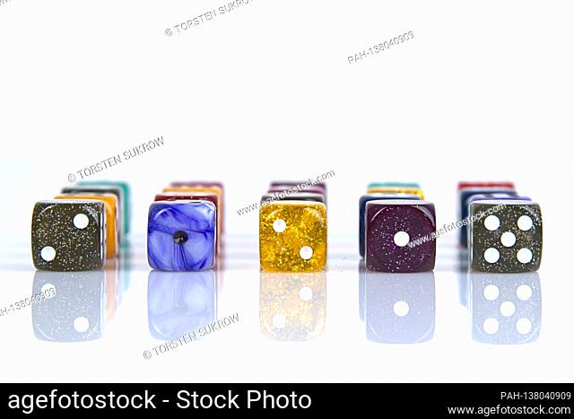 The die is cast"". Colorful dice in a row with a slight reflection on the ground in front of a neutral background. | usage worldwide. - /Deutschland