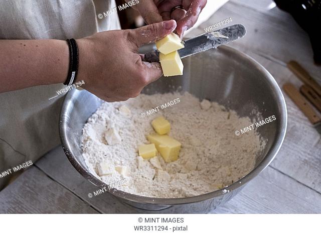 High angle close up of person mixing butter and flour for a crumble in metal bowl