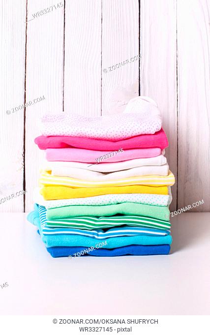 Colorful baby clothes of folded pile on a white background
