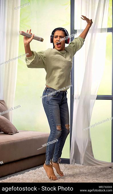 A YOUNG WOMAN HAPPILY DANCING WHILE LISTENING TO MUSIC