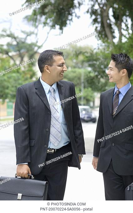 Two businessmen looking at each other and smiling