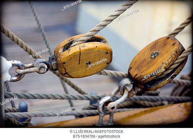 closeup of wooden pulleys, ropes and shackles on deck of sailing boat