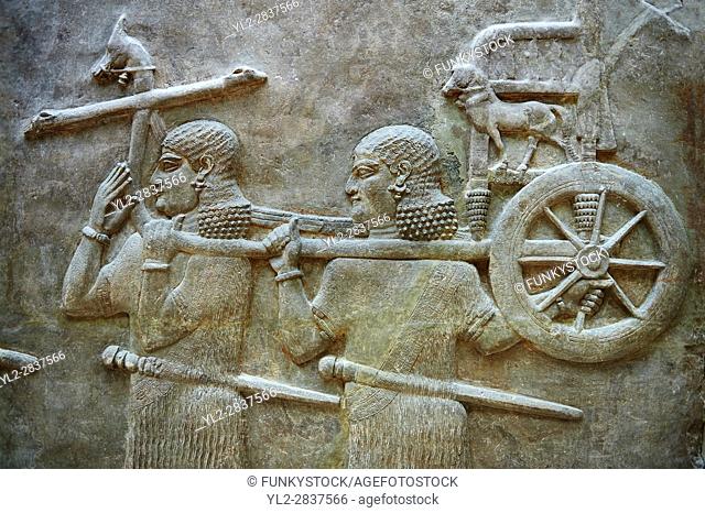 Stone relief sculptured panel of soldiers carrying a chariot . Facade L. Inv AO 19884 from Dur Sharrukin the palace of Assyrian king Sargon II at Khorsabad