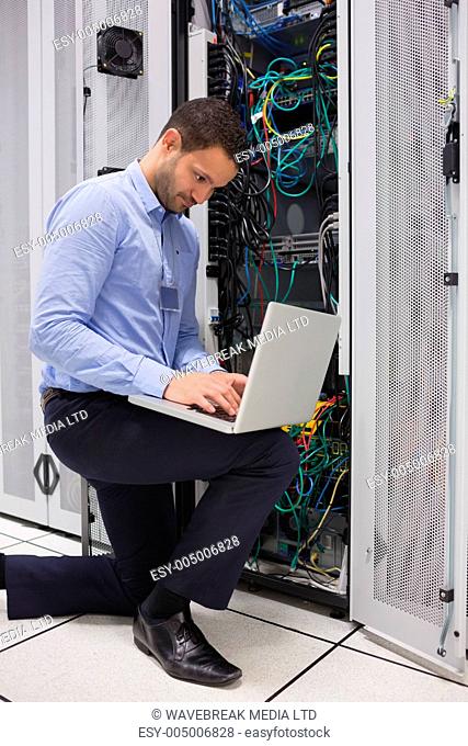 Concentrated technician doing data storage with laptop