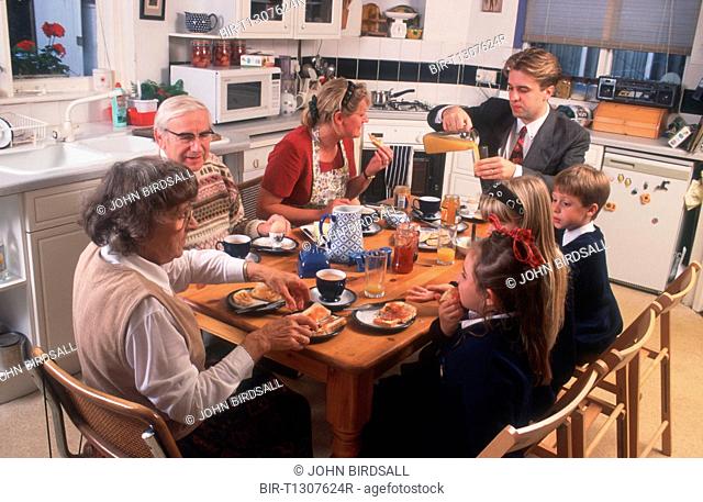 Family group with three generations eating breakfast at kitchen table