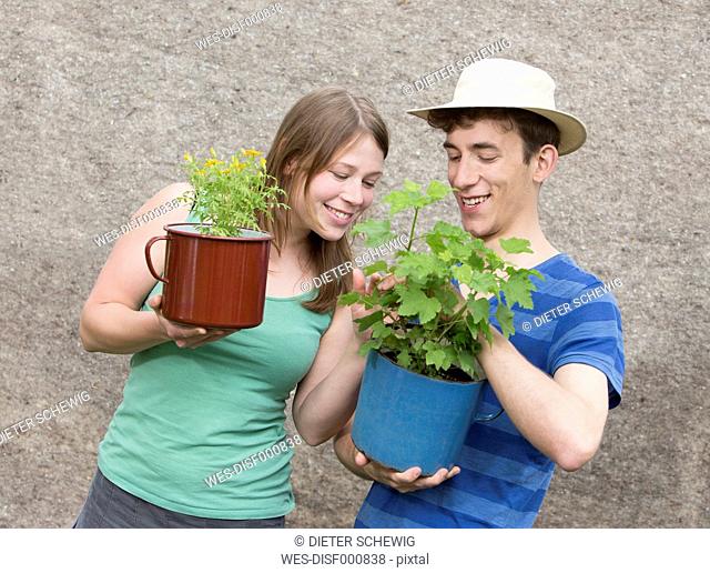 Young couple with two potted plants, Tagetes tenuifolia and Ribes