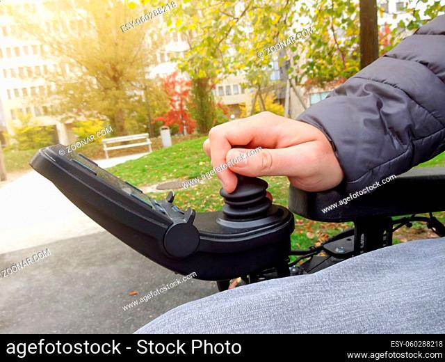 Close up of a disabled person hand driving electric wheelchair using joystick