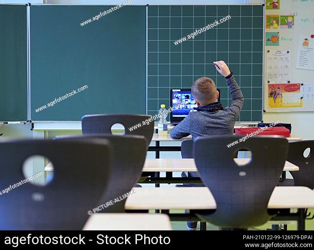 21 January 2021, Brandenburg, Oranienburg: A pupil sits in a classroom of the Comenius School during a lesson at the laptop standing in front of a blackboard on...