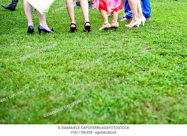 Green grass with feet and shoes of women, wedding attendees
