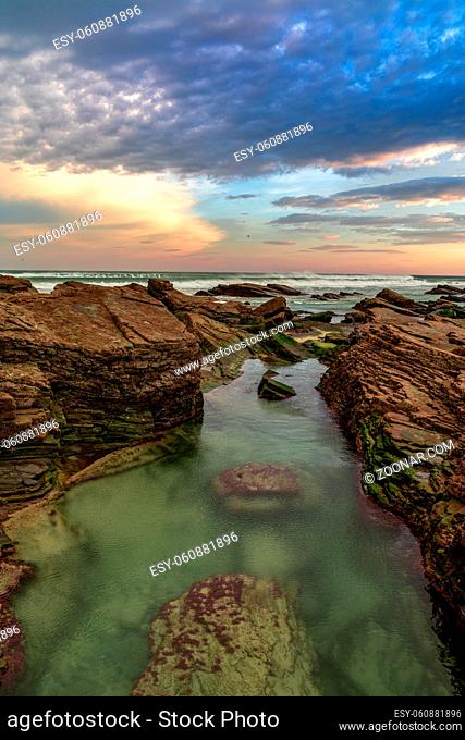 Beautiful sunrise at the Playa de las Catedrales Beach in Galicia in northern Spain with tidal pools in the foreground